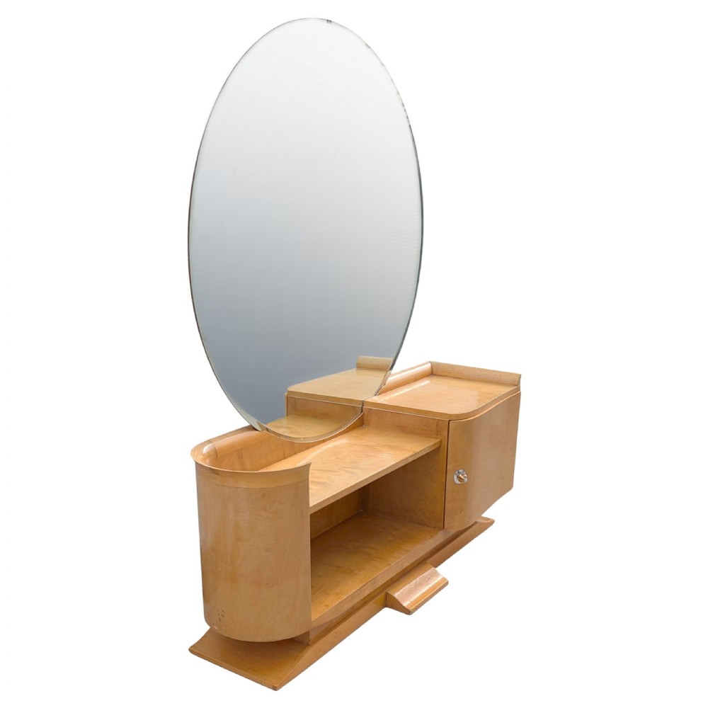 A 1930s Art Deco blonde wood dressing table featuring a massive circular mirror, asymmetrical open shelving, and a curved side pedestal cabinet. View II