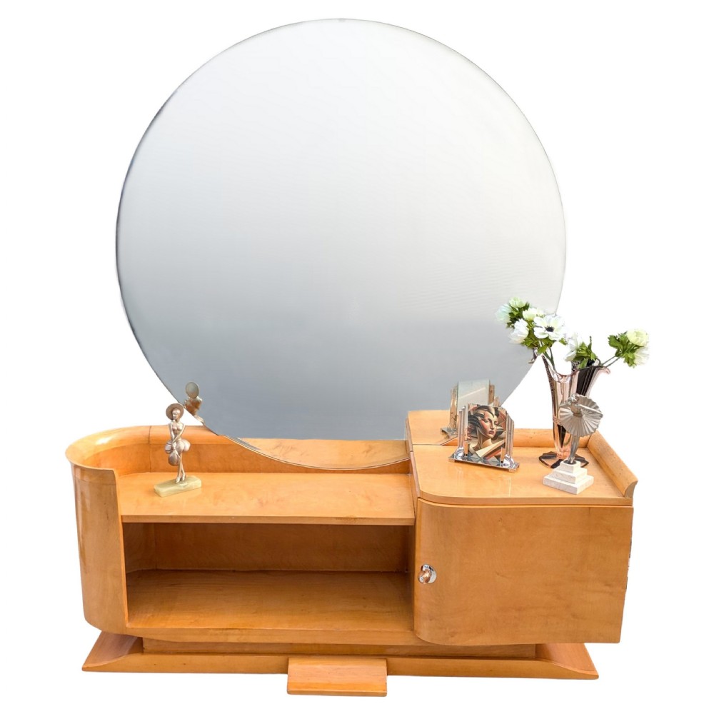 A 1930s Art Deco blonde wood dressing table featuring a massive circular mirror, asymmetrical open shelving, and a curved side pedestal cabinet.