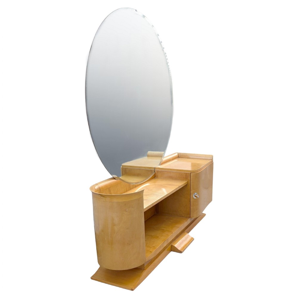 A 1930s Art Deco blonde wood dressing table featuring a massive circular mirror, asymmetrical open shelving, and a curved side pedestal cabinet. View VIII