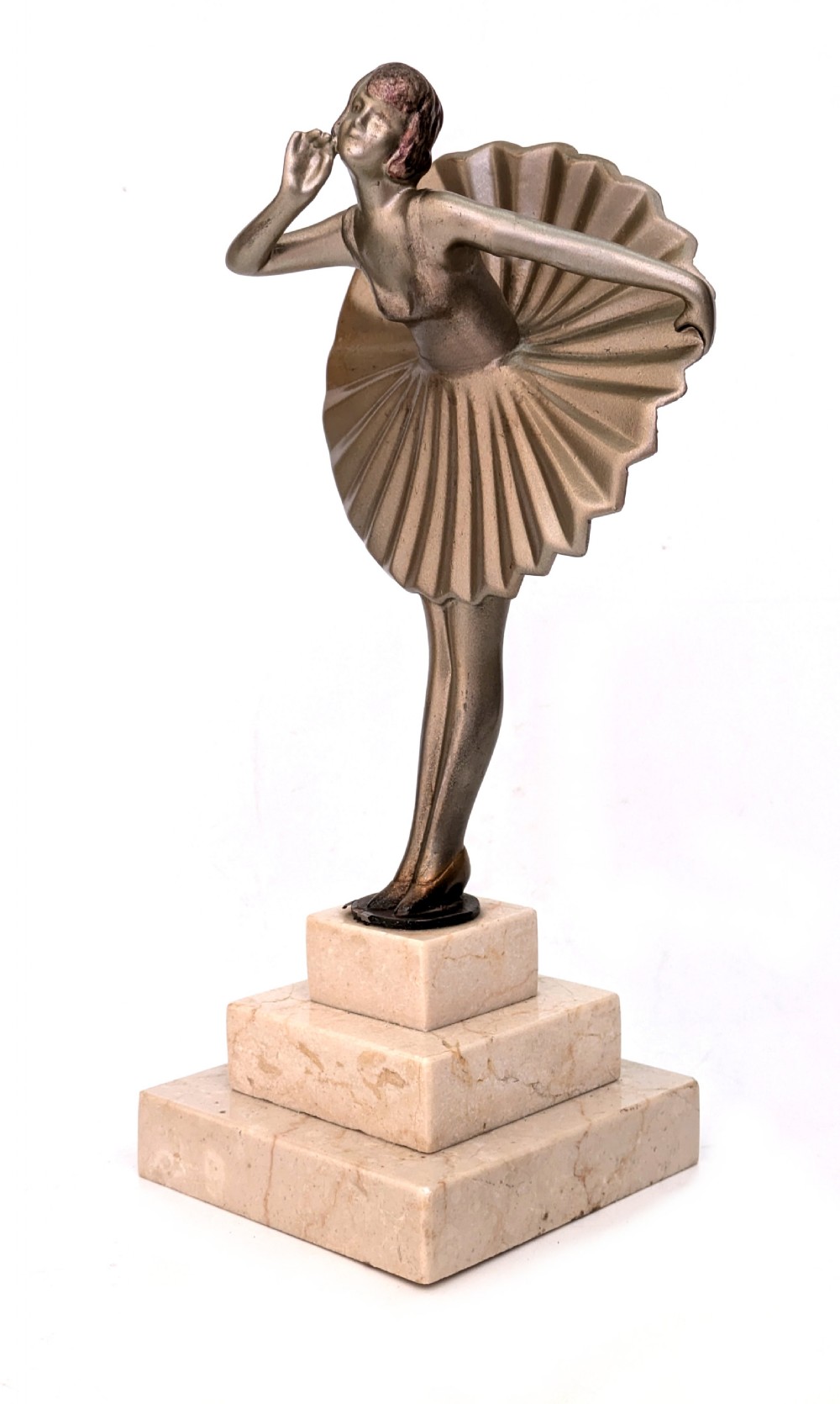 An Art Deco spelter sculpture depicting a female dancer in a stylized fan dress, standing on a three-tiered beige marble plinth. View II