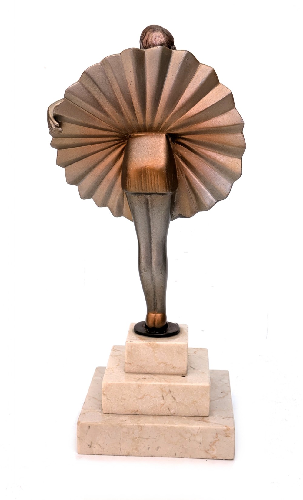 An Art Deco spelter sculpture depicting a female dancer in a stylized fan dress, standing on a three-tiered beige marble plinth. View IV