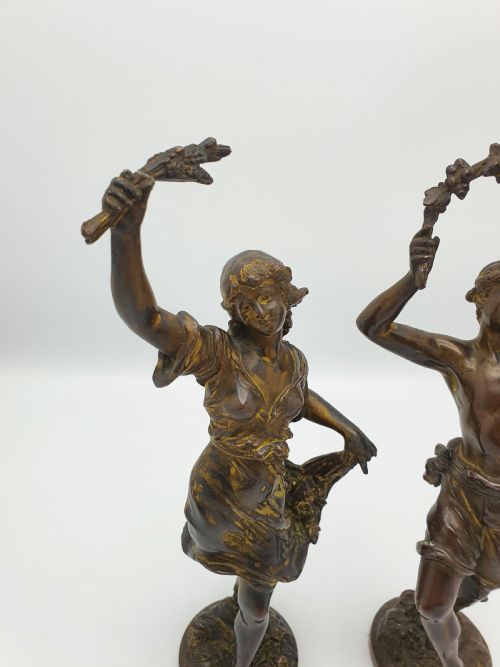 fig 1. A pair of dark patinated bronze figurines depicting male and female harvest dancers holding floral garlands.