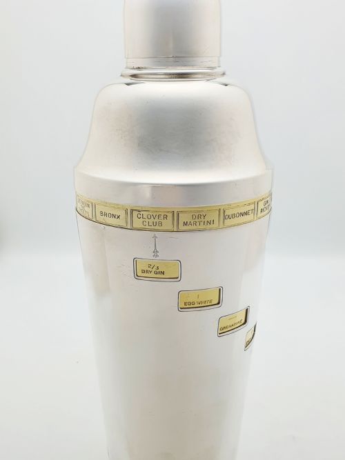fig 5. A vintage silver-plated cocktail shaker featuring a rotating outer body with cutout windows displaying drink ingredient recipes.