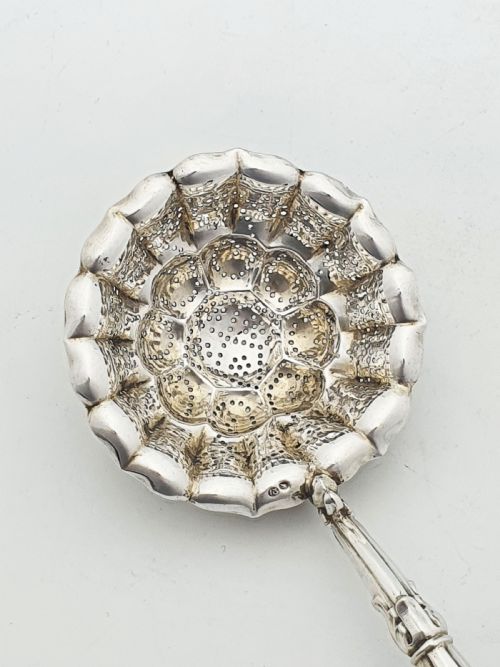 fig 1. A late nineteenth-century Continental silver tea strainer featuring a fluted pierced bowl attached to a dark turned wooden handle.
