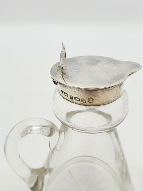 fig 1. A pair of clear glass conical whiskey noggins with sterling silver collars, hinged lids, and applied glass loop handles.