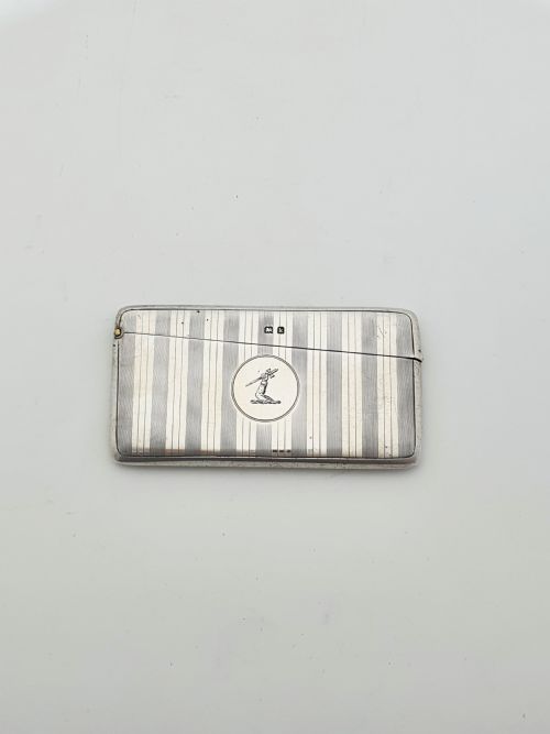 fig 1. An open Edwardian sterling silver card box featuring an engine-turned striped pattern, British hallmarks, and an engraved central crest.