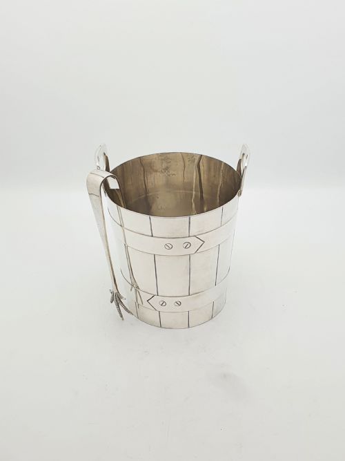 fig 1. An Edwardian silver-plated ice bucket shaped like a wooden barrel with integrated handles alongside matching claw-foot ice tongs.