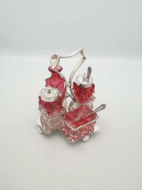 fig 1. An Edwardian silver-plated stand holding four diamond-cut cranberry flashed glass condiment bottles and jars.