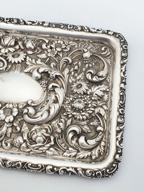 fig 1. A rectangular sterling silver tray decorated with raised floral repousse patterns and an unengraved central cartouche.