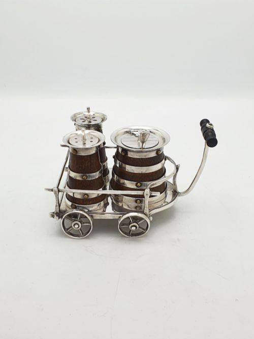fig 1. An antique Victorian silver-plated condiment set crafted as a miniature four-wheeled trolley holding three oak barrel-shaped containers.
