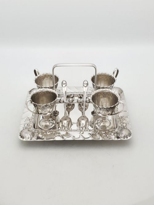 fig 1. An Edwardian silver-plated egg cruet set with four embossed egg cups, four spoons, and an ornate tray with a central carry handle.
