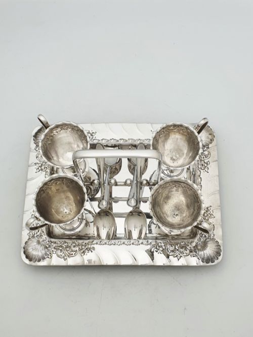 fig 2. An Edwardian silver-plated egg cruet set with four embossed egg cups, four spoons, and an ornate tray with a central carry handle.