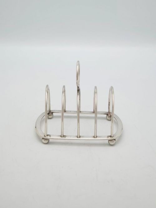 fig 1. A small late Victorian sterling silver toast rack featuring five arched divisions, a central ring handle, and four ball feet.