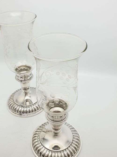 fig 1. A pair of silver-plated candlestick bases fitted with clear etched glass hurricane shades featuring subtle floral patterns.