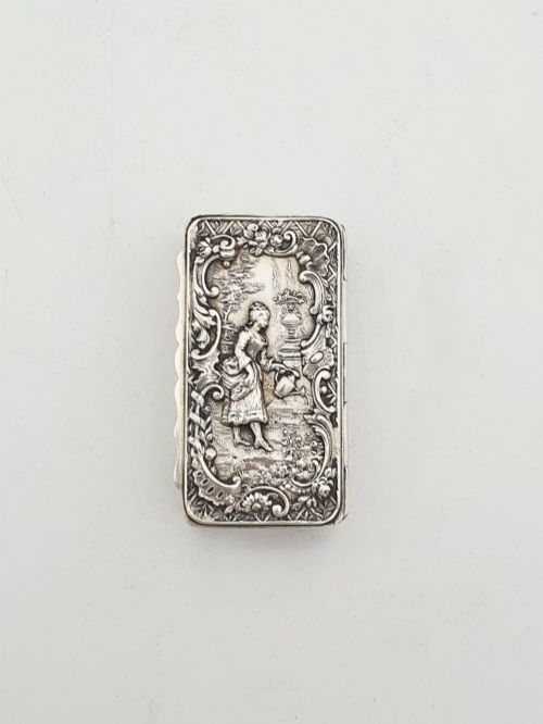 fig 2. A rectangular Victorian sterling silver snuff box with intricate repousse relief work depicting a pastoral scene surrounded by floral scrollwork.