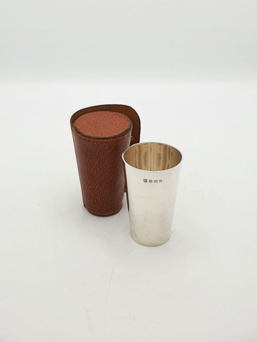 fig 1. A polished Art Deco sterling silver travel beaker standing beside its fitted tan leather carrying case.