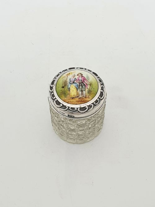 fig 1. An Edwardian round cut-glass vanity jar featuring a sterling silver mounted lid inset with a hand-painted porcelain plaque depicting an eighteenth-century courting couple.