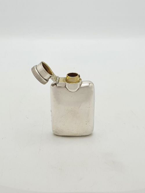 fig 1. A small sterling silver rectangular hip flask with rounded corners and a hinged bayonet cap set against a plain white background.
