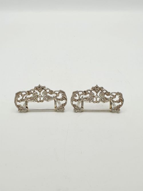 fig 1. A pair of Victorian sterling silver place card holders featuring detailed cherubs framed by pierced scrolling foliage.