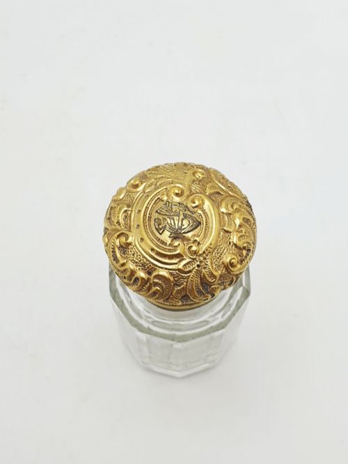 fig 1. A clear faceted cut glass scent bottle featuring an embossed gilt sterling silver cap.