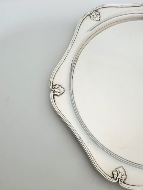 fig 1. An Art Deco silver-plated circular cocktail tray featuring a scalloped rim decorated with stylised leaf motifs.