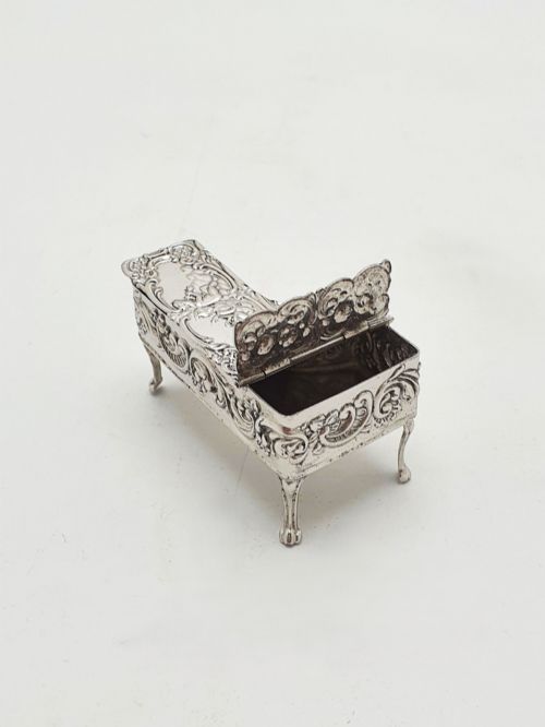 fig 1. A miniature sterling silver trinket box shaped like a grand piano with embossed cherub motifs and cabriole legs.