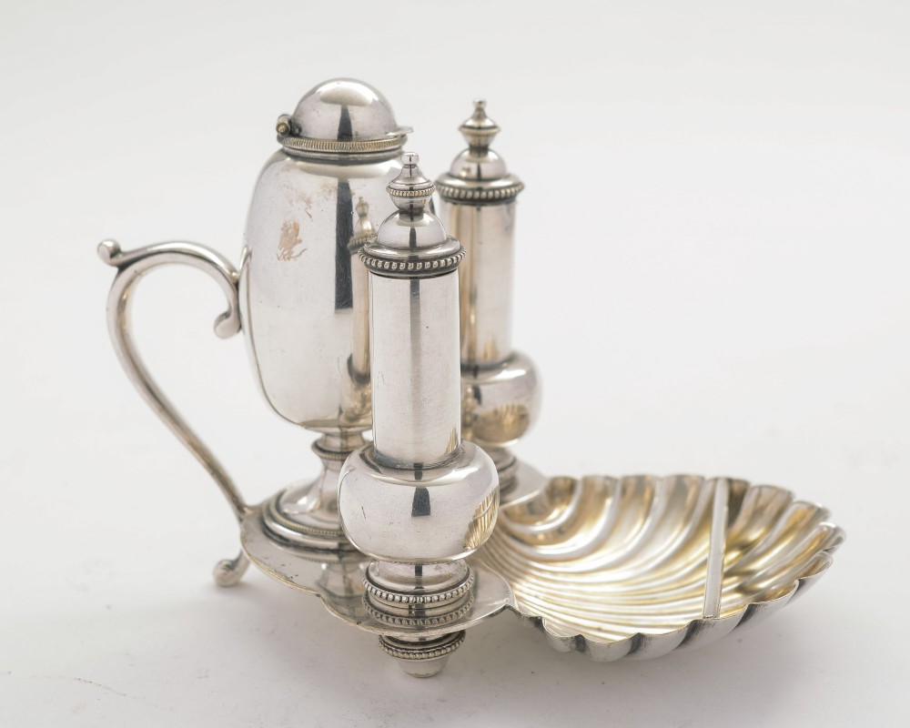 An antique silver-plated table lighter featuring a central fuel urn, companion canisters, and a shell-shaped ash tray on a fitted base.