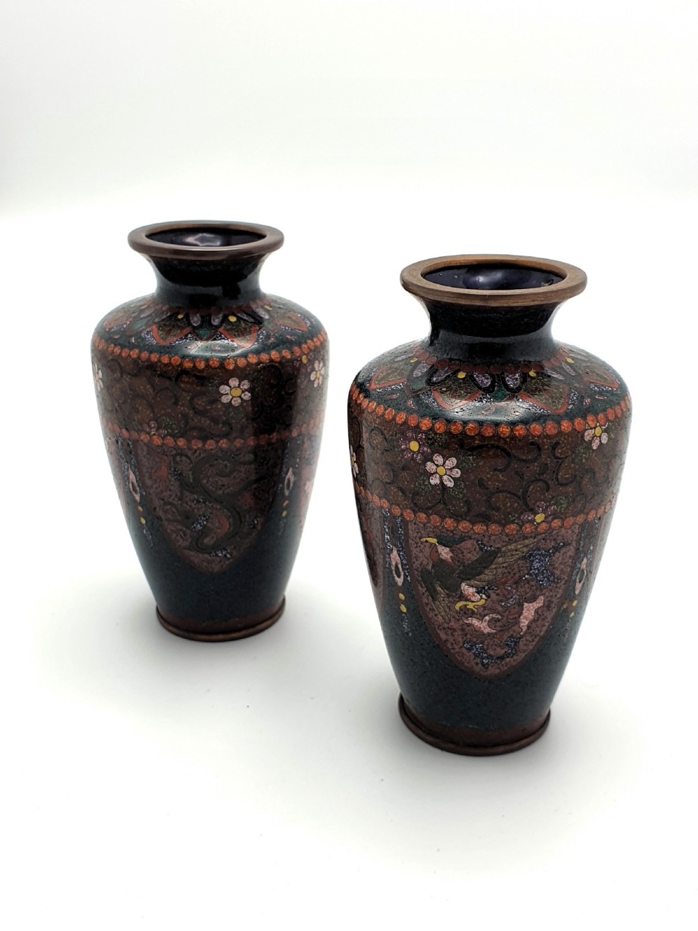 A pair of small dark brown Japanese cloisonne enamel vases decorated with bird and floral motifs.