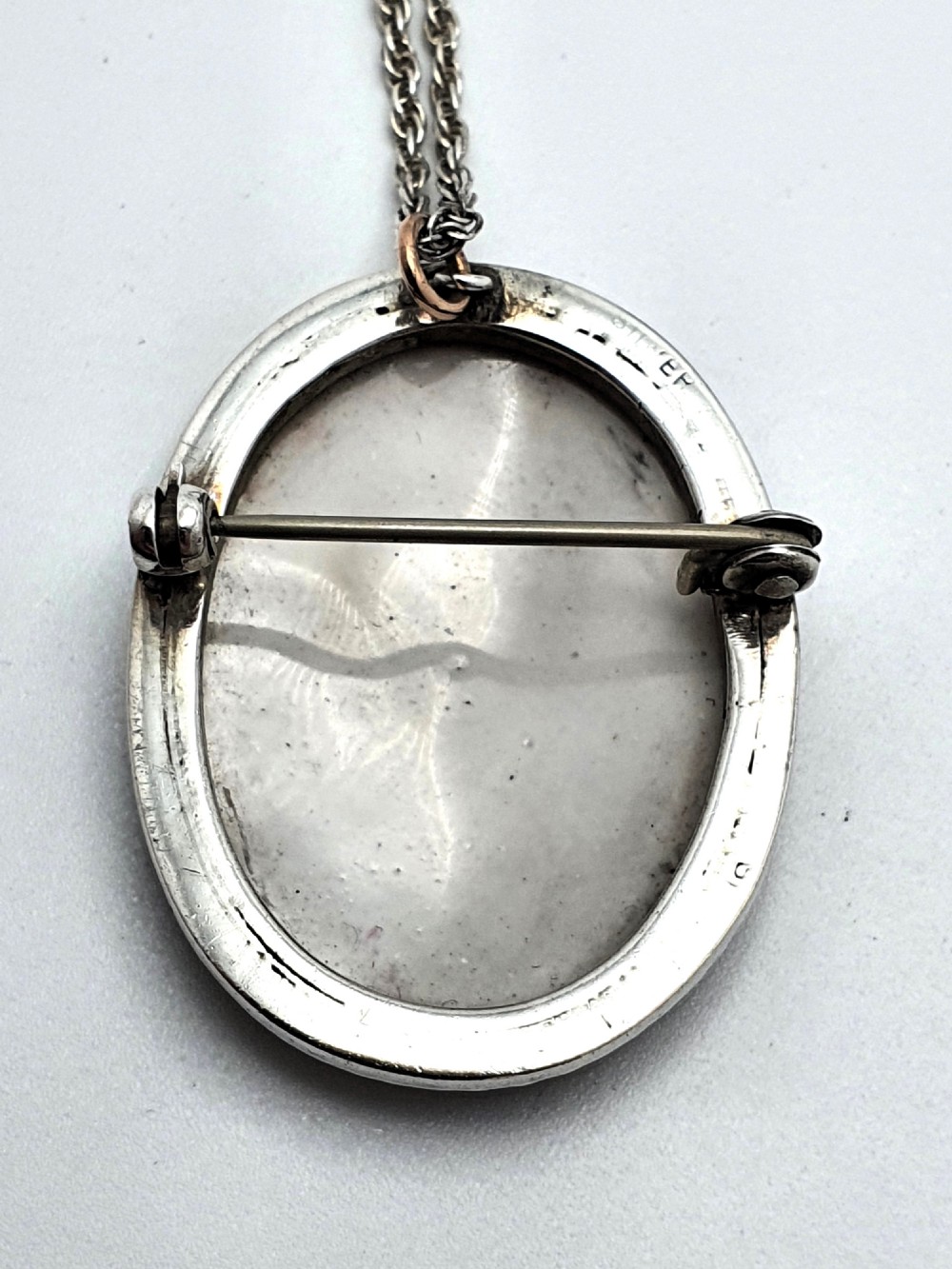 An oval silver pendant brooch featuring a hand-painted portrait of an eighteenth-century woman, presented inside a blue velvet box. View VI