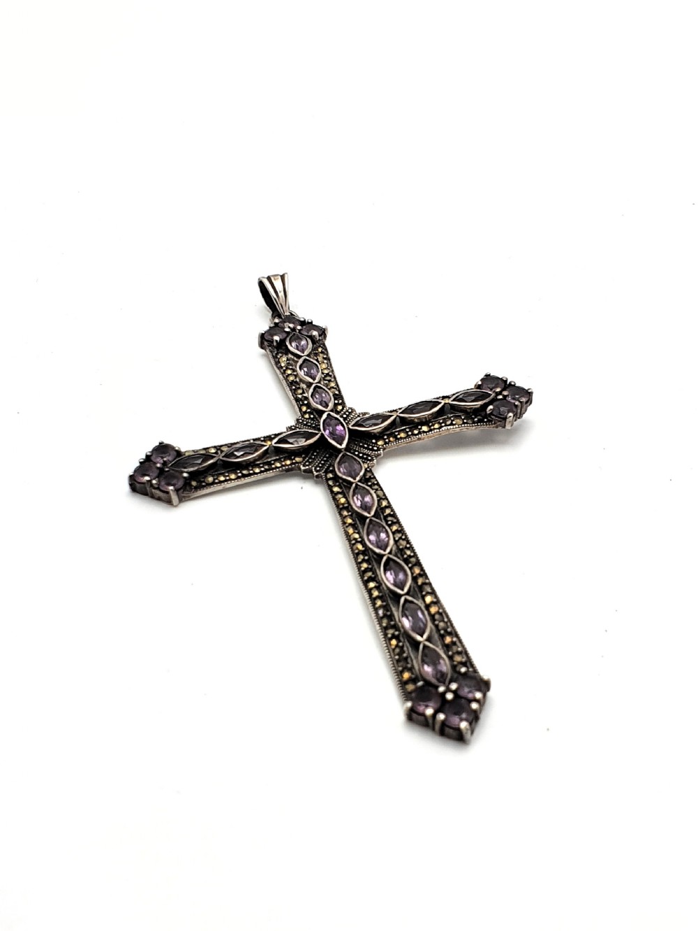 A silver cross pendant set with marquise-cut purple amethysts and detailed marcasite stones.