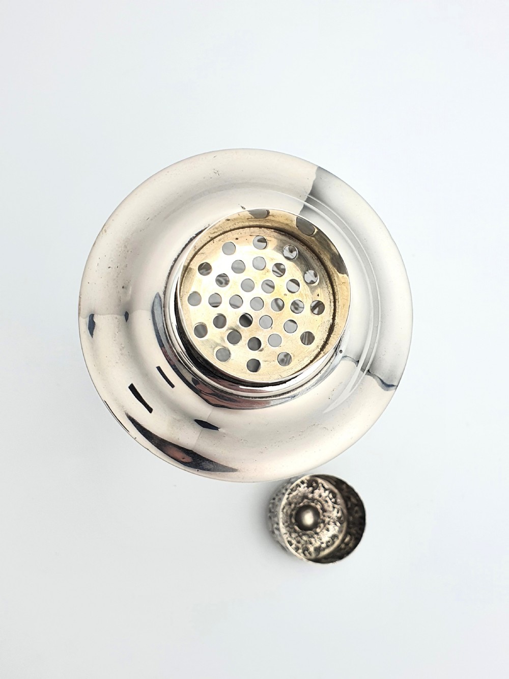 An antique clear glass cocktail shaker featuring etched silver overlay foliage patterns and relief-carved sterling silver mounts depicting cherubs. View IX