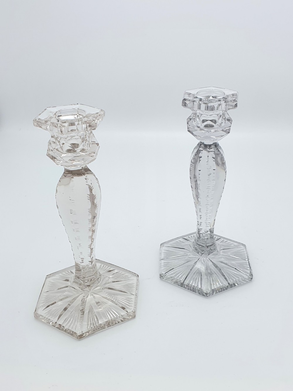 A pair of clear cut-glass candlesticks featuring faceted stems and starburst hexagonal bases holding tall cream taper candles. View III