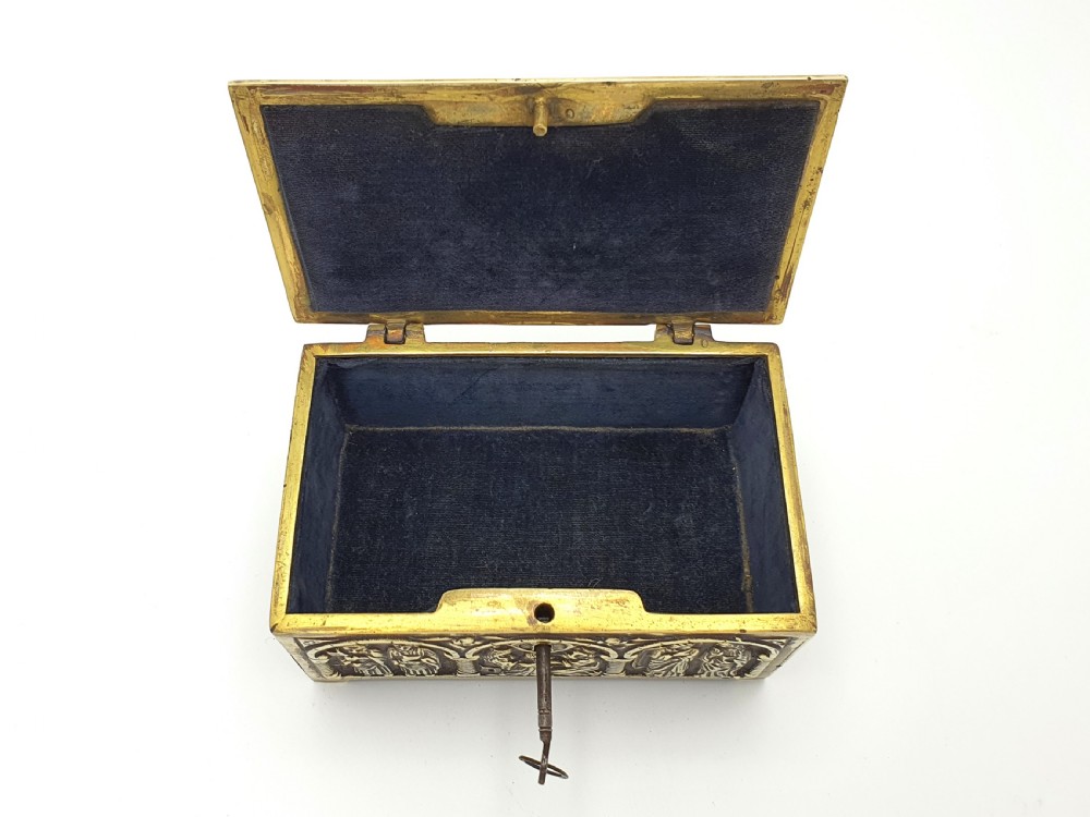 A rectangular brass jewellery box decorated with relief carvings of figures framed within arched arcades. View III