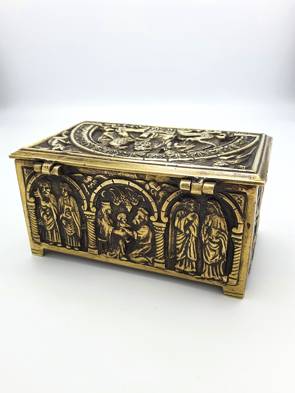 A rectangular brass jewellery box decorated with relief carvings of figures framed within arched arcades. View V