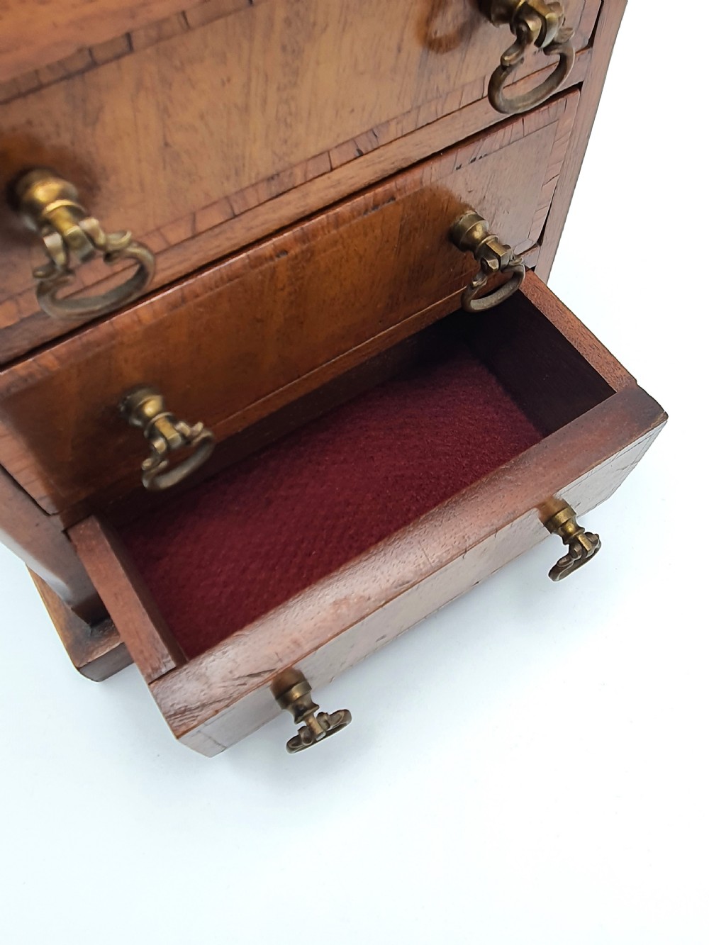 A small mahogany three-drawer miniature chest with brass drop handles and inlaid wood banding. View III