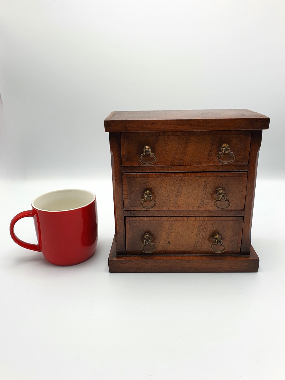 A small mahogany three-drawer miniature chest with brass drop handles and inlaid wood banding. View IV