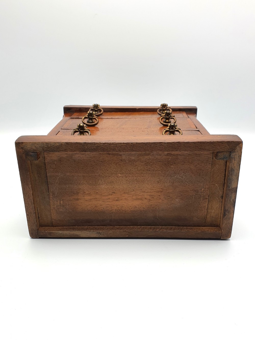 A small mahogany three-drawer miniature chest with brass drop handles and inlaid wood banding. View VIII