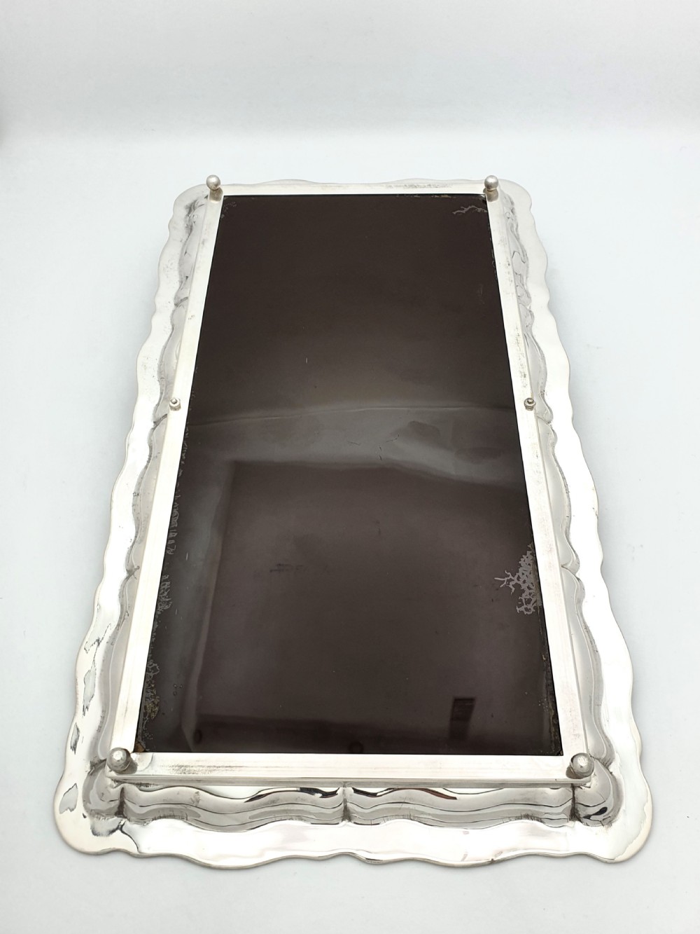 A rectangular silver-plated tray with a scalloped border featuring a deep cobalt blue glass mirror insert engraved with a grapevine and leaf motif. View V
