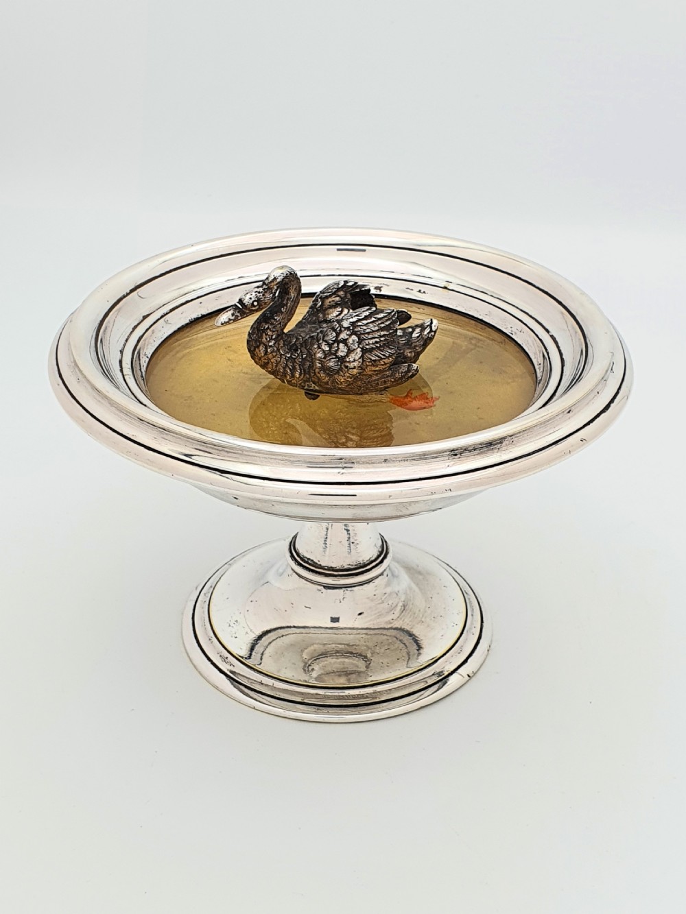 A circular silver pedestal comport featuring a central cast silver swan figure mounted inside a shallow basin.