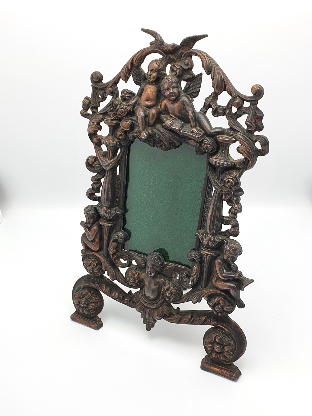 An ornate dark bronze Edwardian cast iron picture frame decorated with cherubs, miniature side columns, scrolling foliate detailings, and a green felt insert. View II