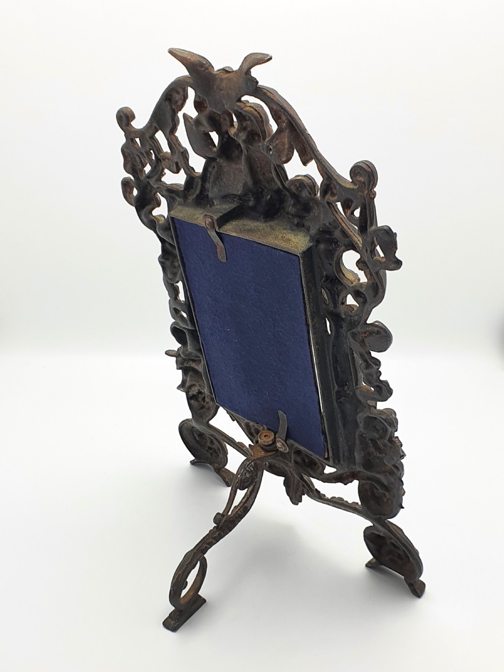 An ornate dark bronze Edwardian cast iron picture frame decorated with cherubs, miniature side columns, scrolling foliate detailings, and a green felt insert. View V