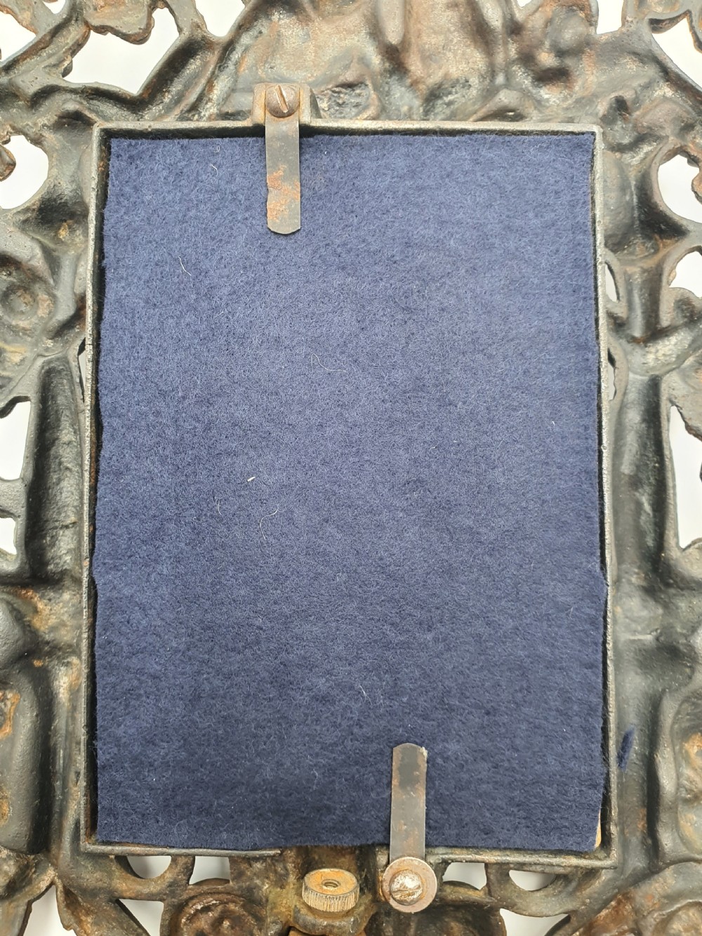 An ornate dark bronze Edwardian cast iron picture frame decorated with cherubs, miniature side columns, scrolling foliate detailings, and a green felt insert. View VII