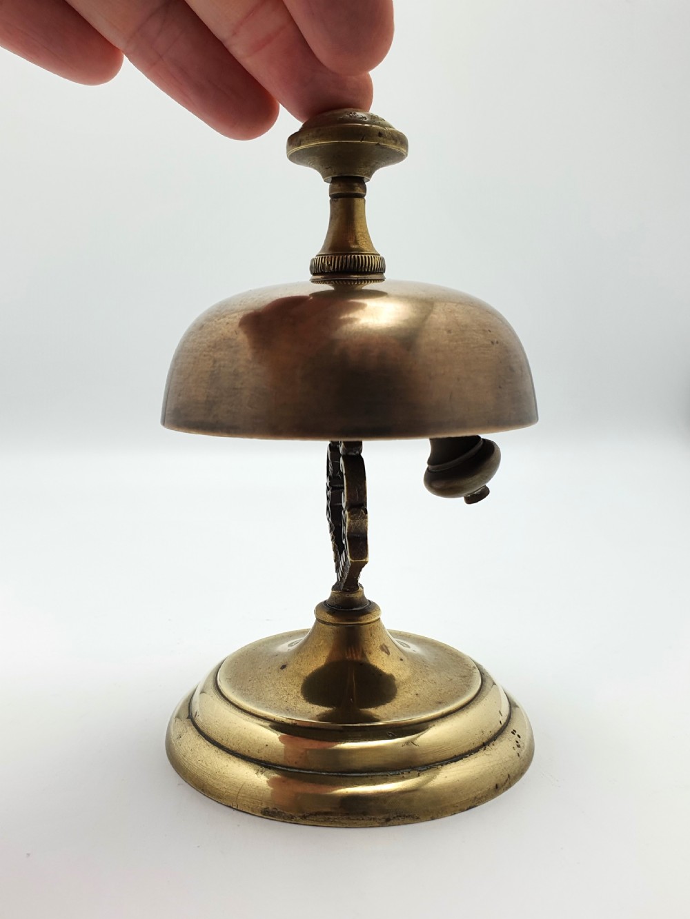 A late Victorian brass and bronze counter bell featuring a stepped circular base, dome bell, and push-button mechanism. View X