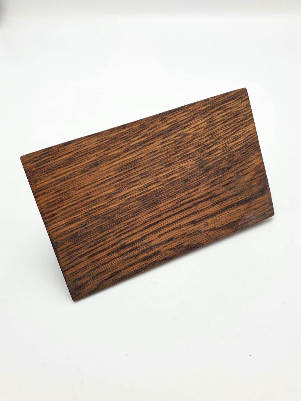A 1920s brass fish-shaped spring clip mounted onto a molded rectangular wooden base. View V