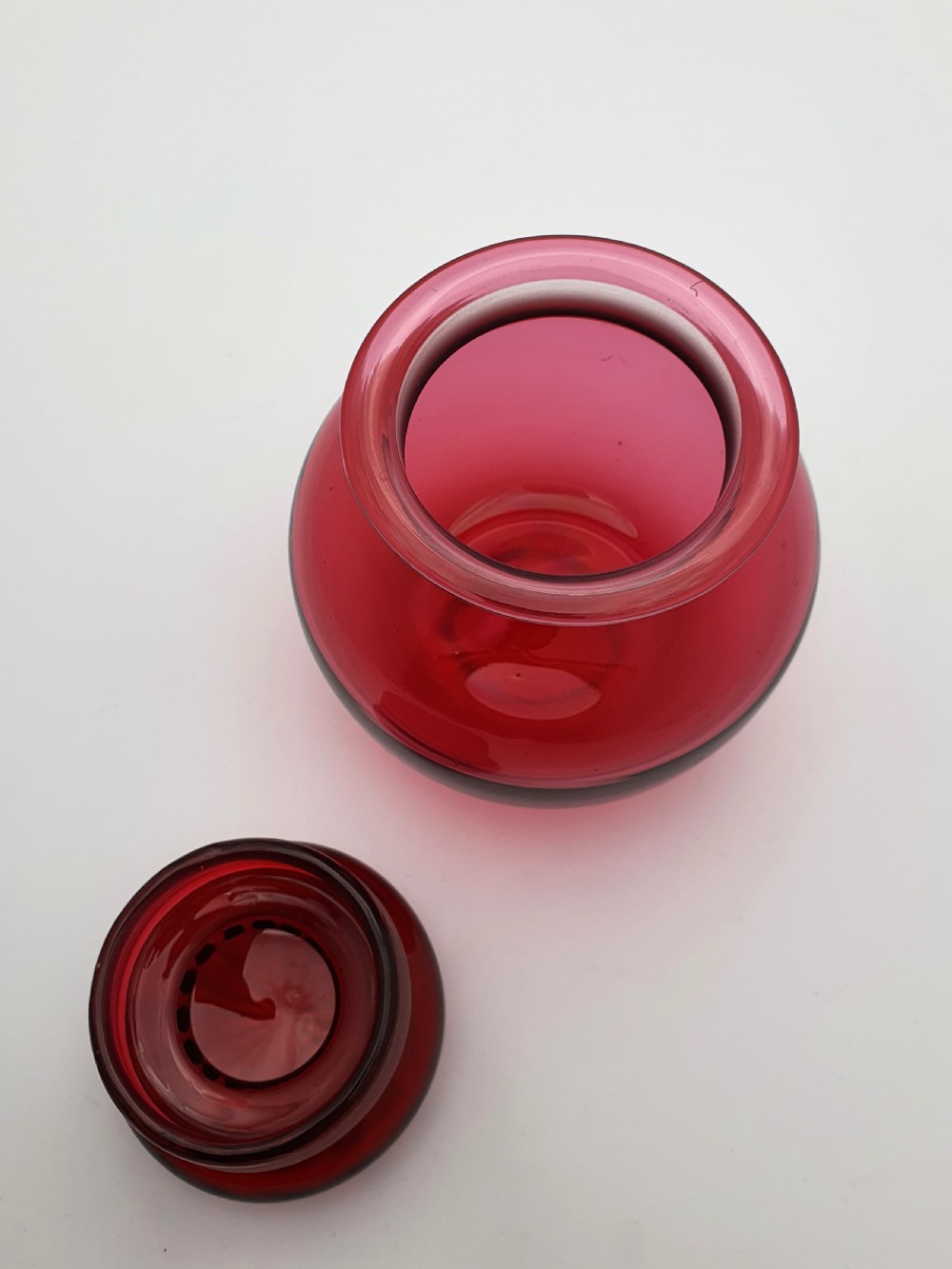 A spherical Edwardian cranberry red glass jar with a flanged neck and a faceted cut-glass stopper. View V