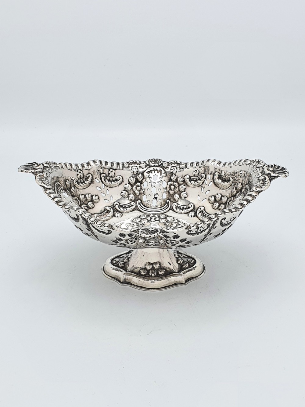 An ornate late Victorian pierced sterling silver basket featuring floral repousse ornamentation and a pedestal base. View III