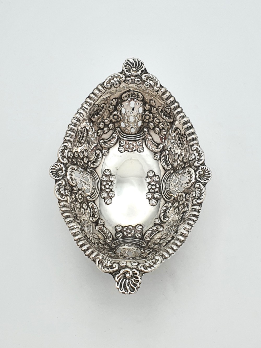 An ornate late Victorian pierced sterling silver basket featuring floral repousse ornamentation and a pedestal base. View IV