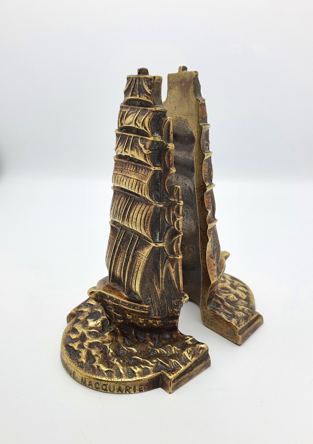 A pair of solid brass bookends featuring a relief design of a tall sailing ship on ocean waves. View II
