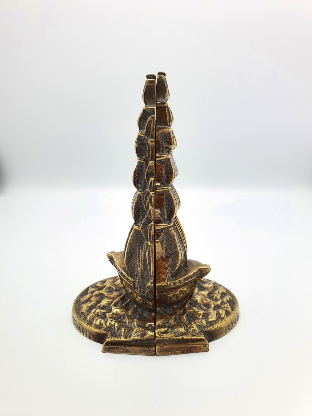 A pair of solid brass bookends featuring a relief design of a tall sailing ship on ocean waves. View III