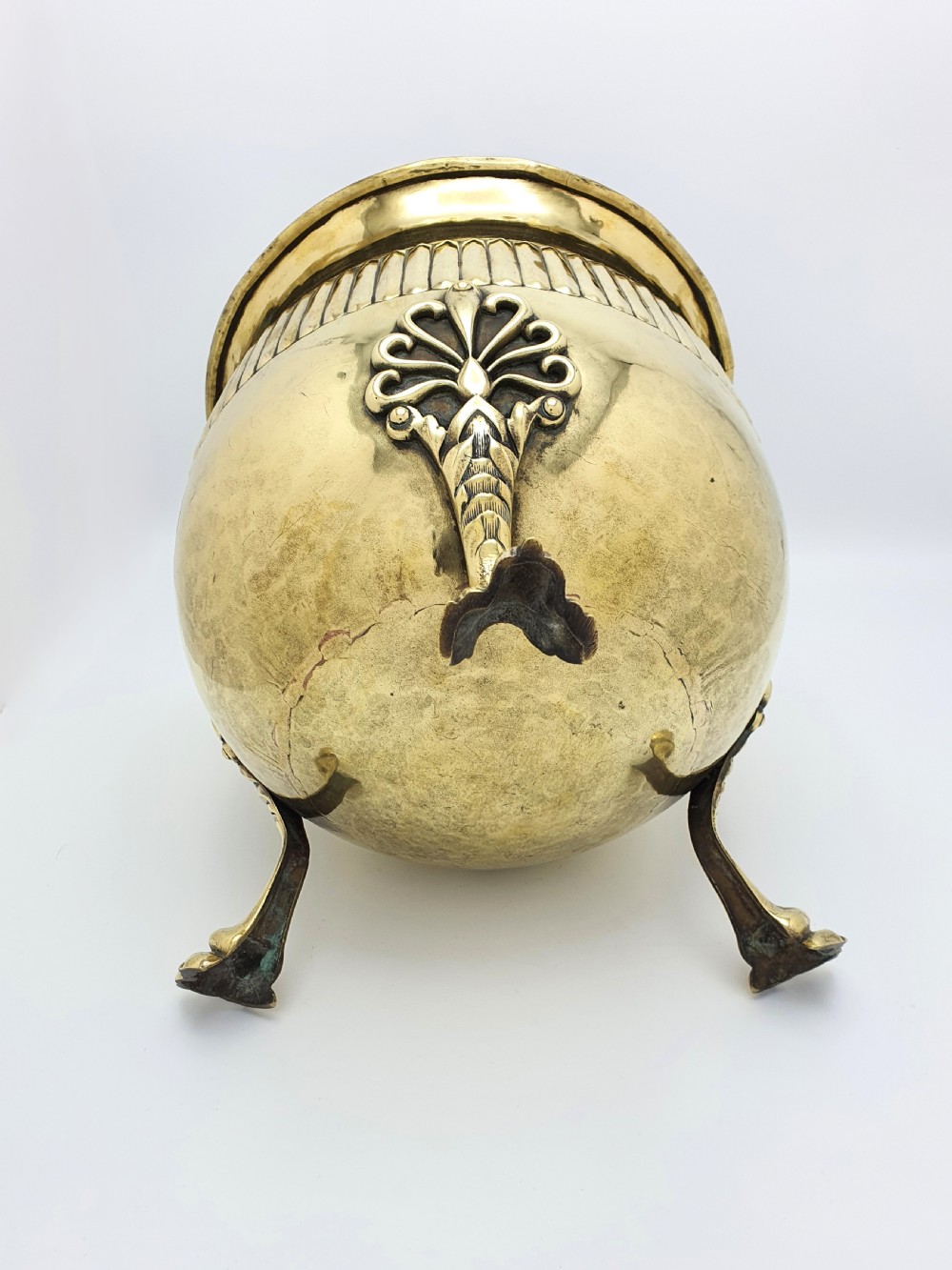 A rounded Edwardian brass jardiniere with a flared rim, a reeded central band, and three decorative cast feet. View III